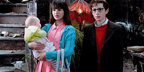 a woman is holding a baby in her arms while standing next to a man and a boy .