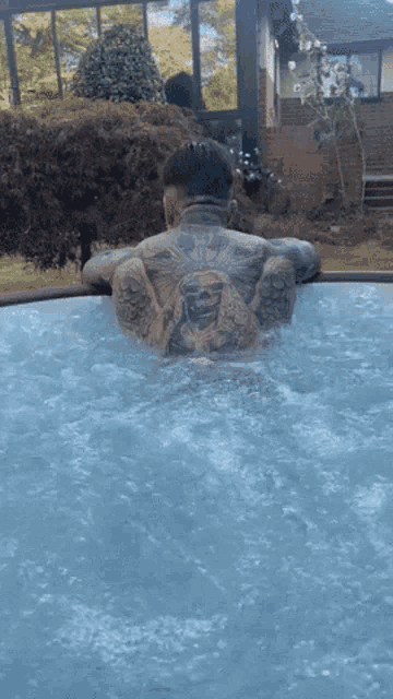a man with a tattoo on his chest is standing in a hot tub .