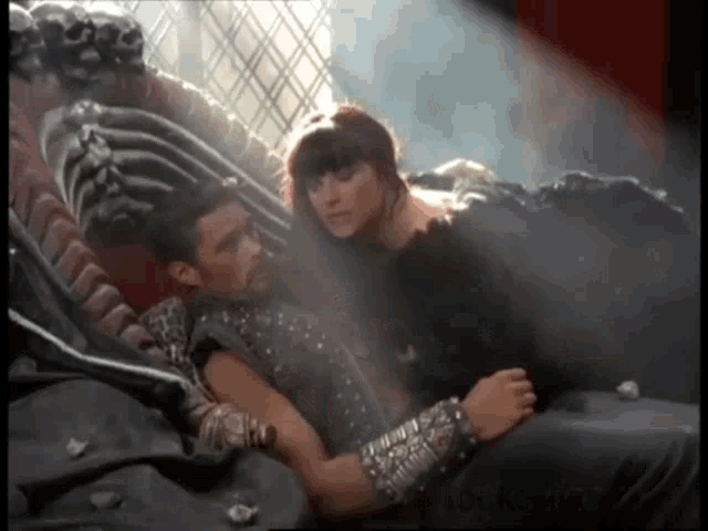 a man and a woman are laying on a couch and the woman has a feather boa around her neck