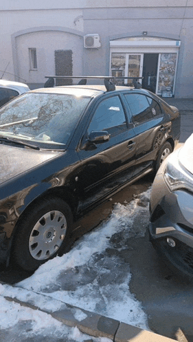 a black car with a roof rack is parked in a parking lot
