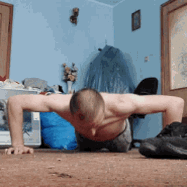a shirtless man is doing push ups in a messy room