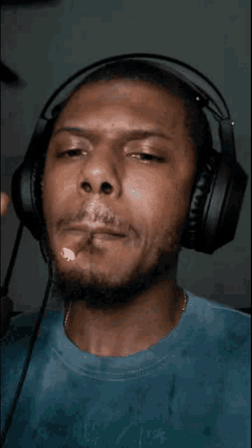 a man wearing headphones and a blue shirt looks at the camera