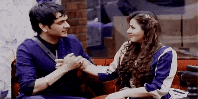 a man and woman are sitting on a couch holding hands