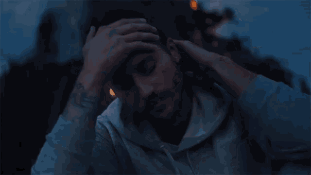 a man with a tattoo on his wrist has his hand on his head