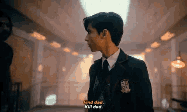 a young man in a suit and tie is standing in a room and talking to someone .