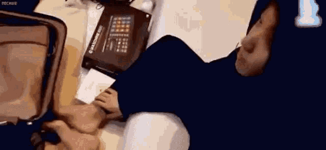 a person is laying on a bed next to a suitcase with their feet in it .