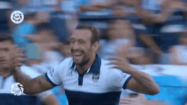 a man in a blue and white striped shirt is laughing