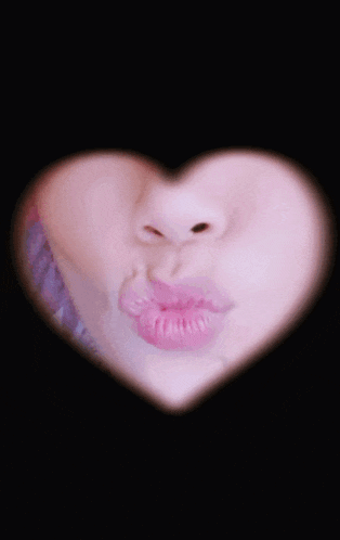 a close up of a woman 's face with her lips blowing a kiss