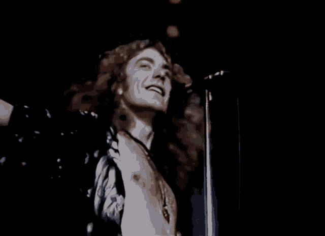 a shirtless man singing into a microphone with the word kashmir on the bottom