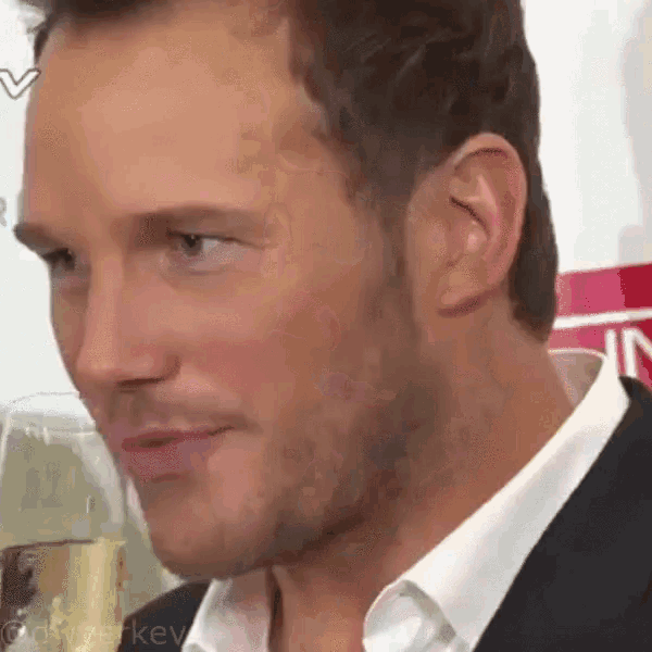 a close up of a man 's face with a glass of champagne in the background