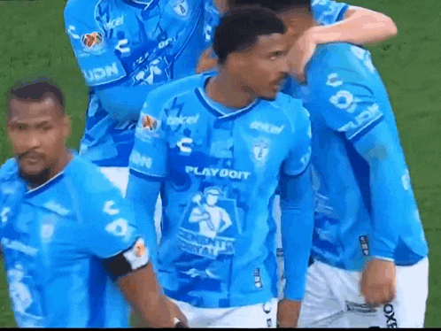 a group of soccer players are standing on a field wearing blue jerseys .