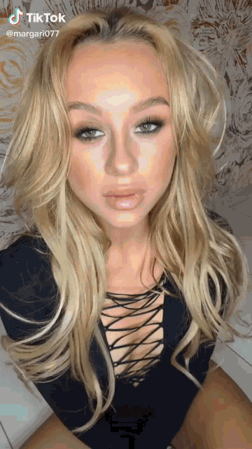 a woman with long blonde hair is wearing a black top