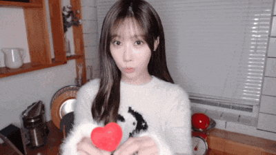 a girl in a white sweater is holding a red heart