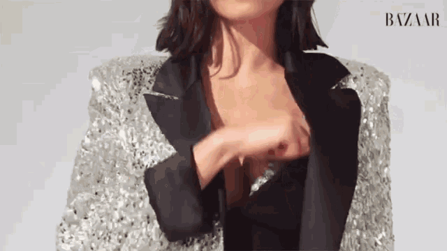 a woman is wearing a black and silver sequined jacket and a black dress .