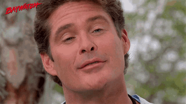 a close up of a man 's face with the word baywatch in red letters
