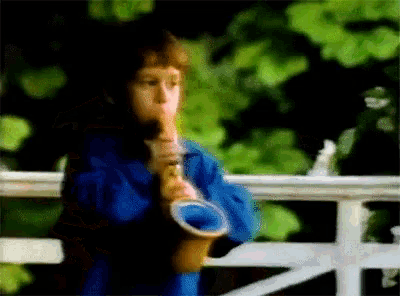 a boy in a blue shirt is playing a trumpet