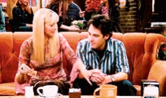 a man and a woman are sitting next to each other on a couch holding hands