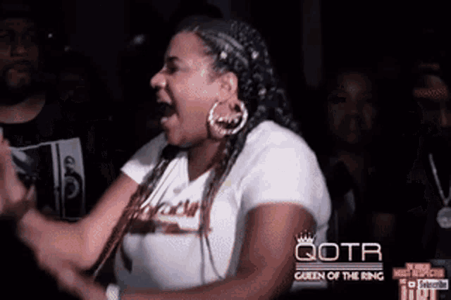 a woman is screaming in front of a crowd and the words queen of the ring are visible
