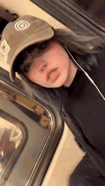 a girl is wearing a hat and headphones while riding a train .
