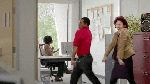 a man and a woman are dancing in an office