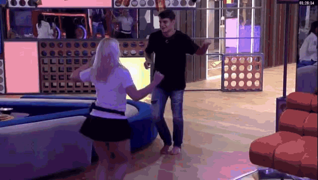 a man and a woman are dancing in front of a screen that says 01:28:14
