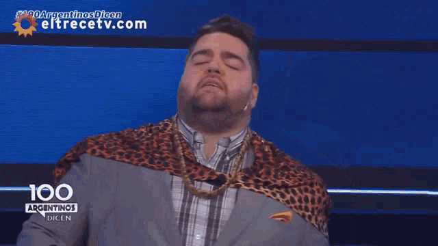 a man with a leopard print scarf around his neck is on a television screen that says 100 argentinos dicen