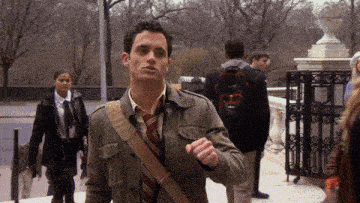 a man wearing a military jacket and tie has a backpack that says tommy hilfiger