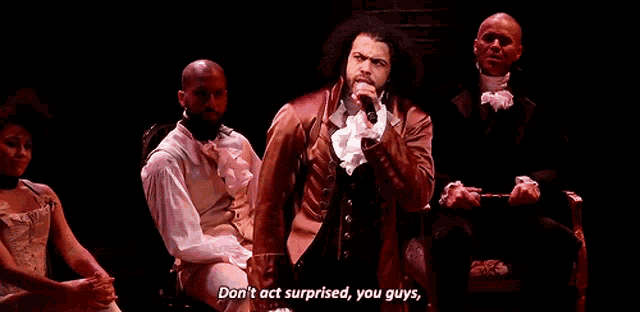 a man is holding a microphone and saying " don 't act surprised , you guys . "