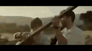 a group of men are standing in a field holding guns in their hands .