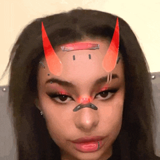 a woman with red horns on her forehead and a piercing in her nose .