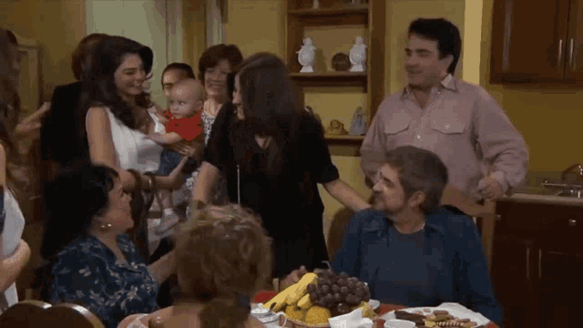 a group of people are gathered around a table with fruits