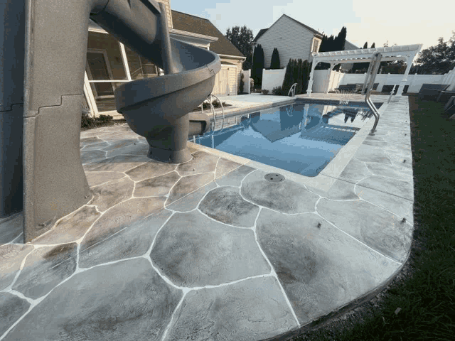 a swimming pool with a slide and a concrete patio