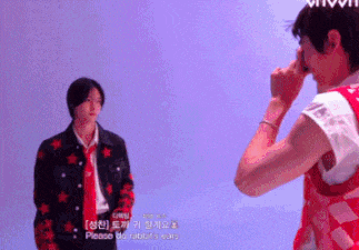 a man in a red vest is taking a picture of another man in a black jacket