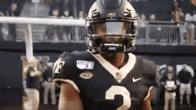 a football player wearing a helmet and a number 2 jersey is standing on a field .