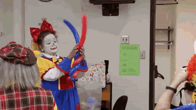 a girl dressed as a clown is holding balloons in a room