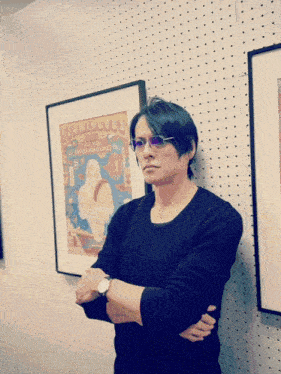 a man is standing in front of a framed poster that says flamingo 's