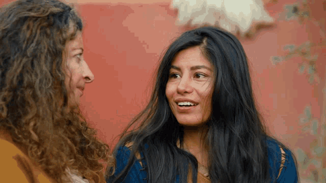 two women are talking to each other and one has a blue shirt on