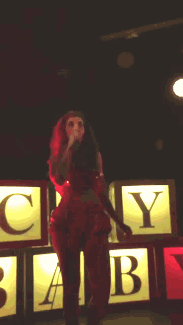 a woman singing on stage in front of a sign that says cry baby