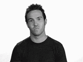 a black and white photo of a man making a funny face with his fists in the air .