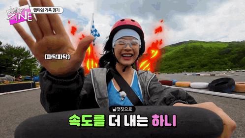 a woman wearing a helmet and goggles is smiling while riding a skateboard on a race track