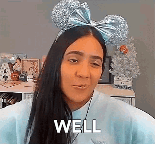 a woman wearing a headband with mickey mouse ears and a bow on it says well .