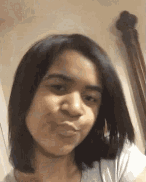 a young woman with short hair is making a funny face while looking at the camera .
