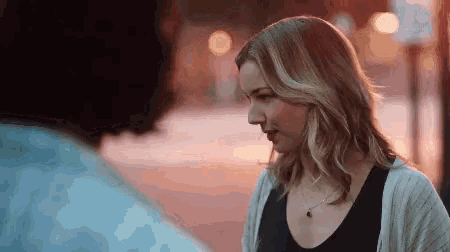 a woman wearing a necklace is looking at a man 's face