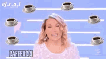 a woman is surrounded by cups of coffee and saucers and is smiling .