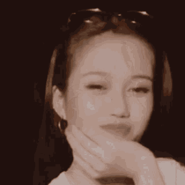 a close up of a woman covering her face with her hand .