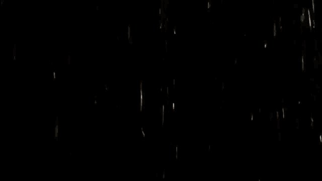 rain is falling in the dark on a black background