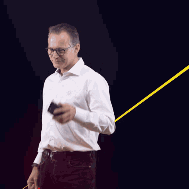 a man wearing glasses and a white shirt talks on a cell phone