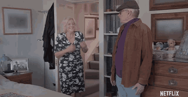 a man and a woman are standing in a room with a netflix logo on the wall