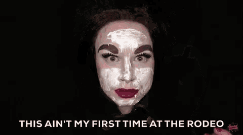 a woman with a white face mask on her face is smoking a cigarette .