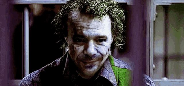 a close up of a man in a joker costume looking at the camera .